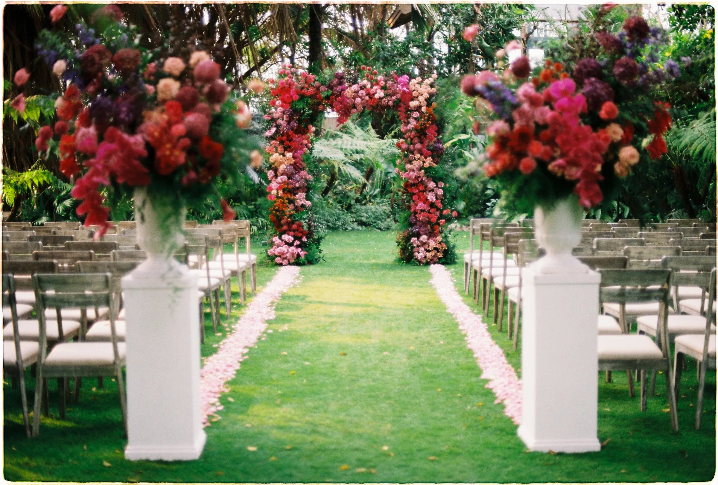 Garden ceremony aisle with tall floral urns at An Lam Retreats, on film