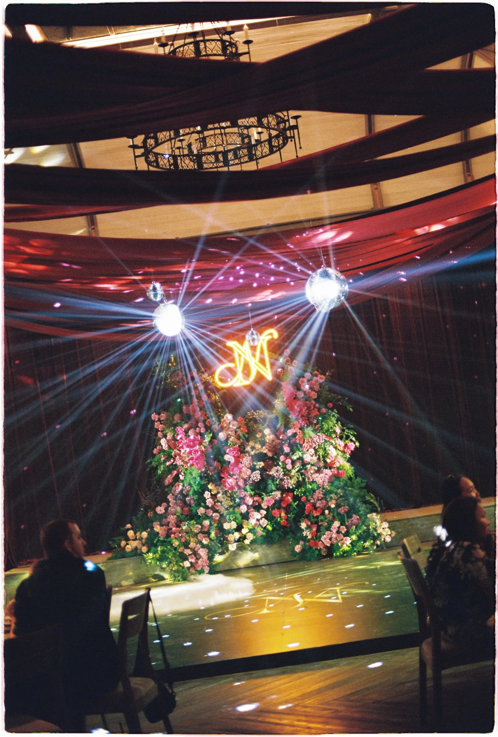 Reception decor with disco balls and a neon monogram, on film