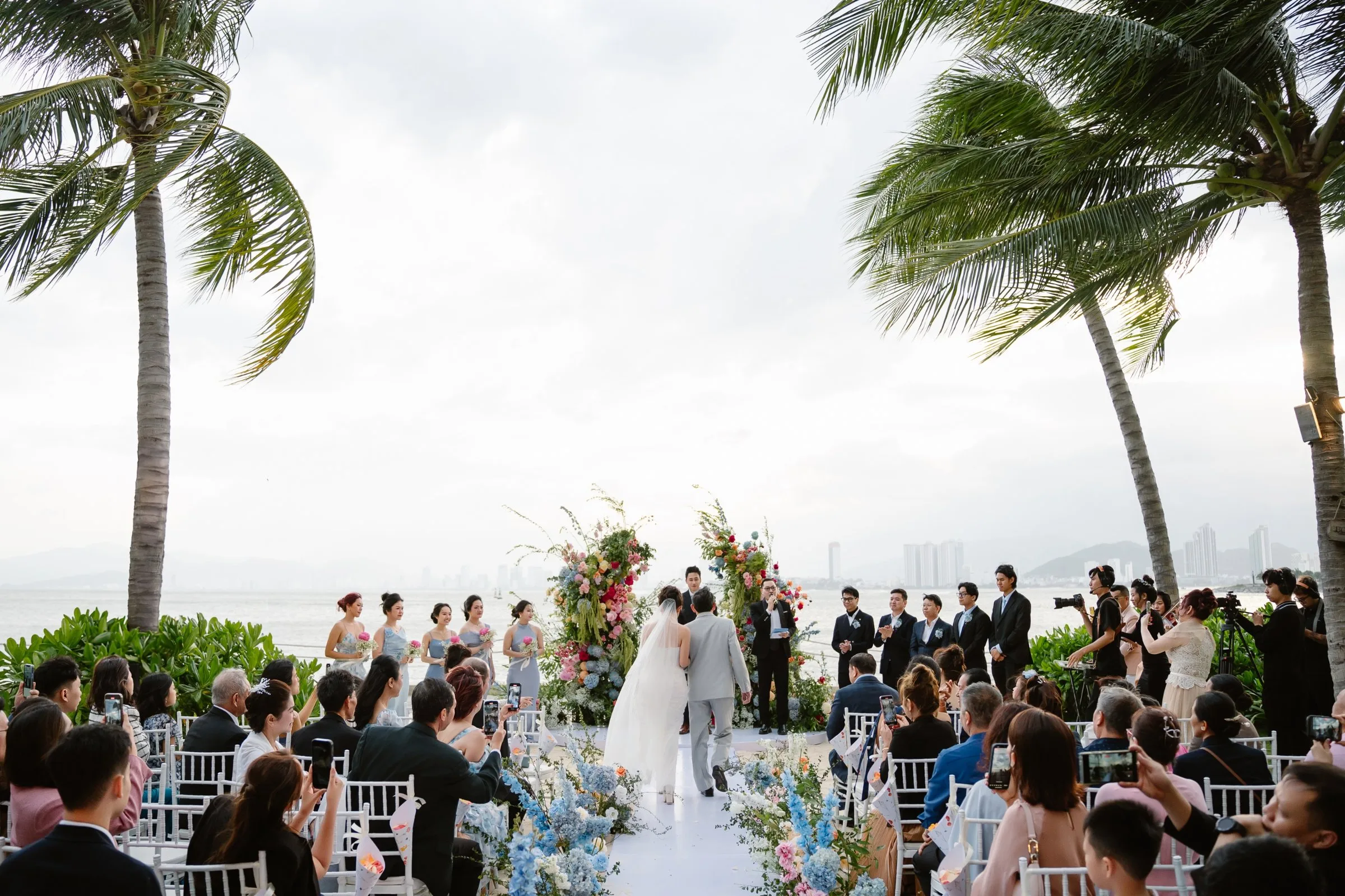 A sunset beach wedding ceremony framed by palm trees at BOMA Resort, Nha Trang