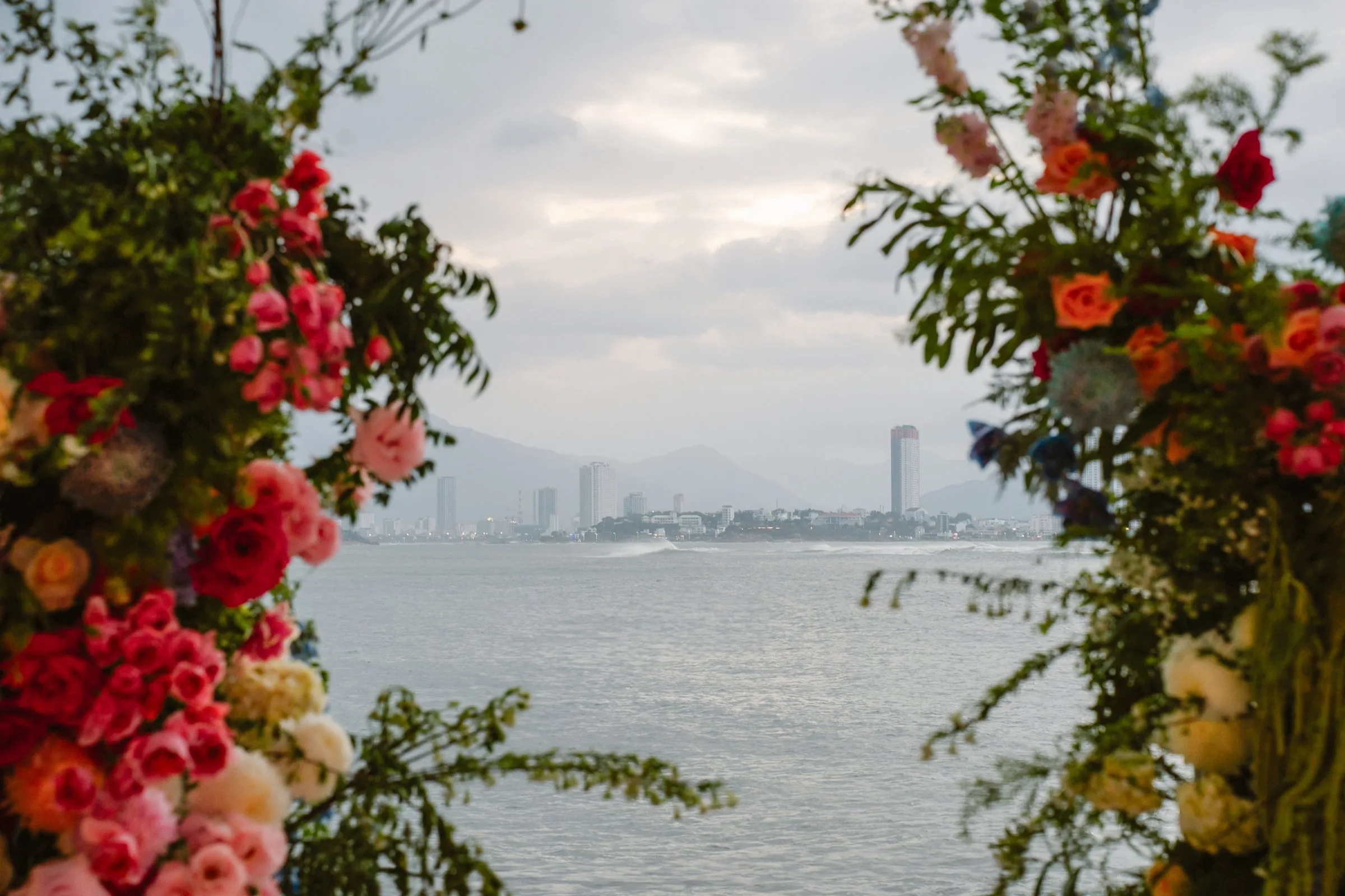 Nha Trang bay and city skyline framed by a floral wedding arch at BOMA Resort