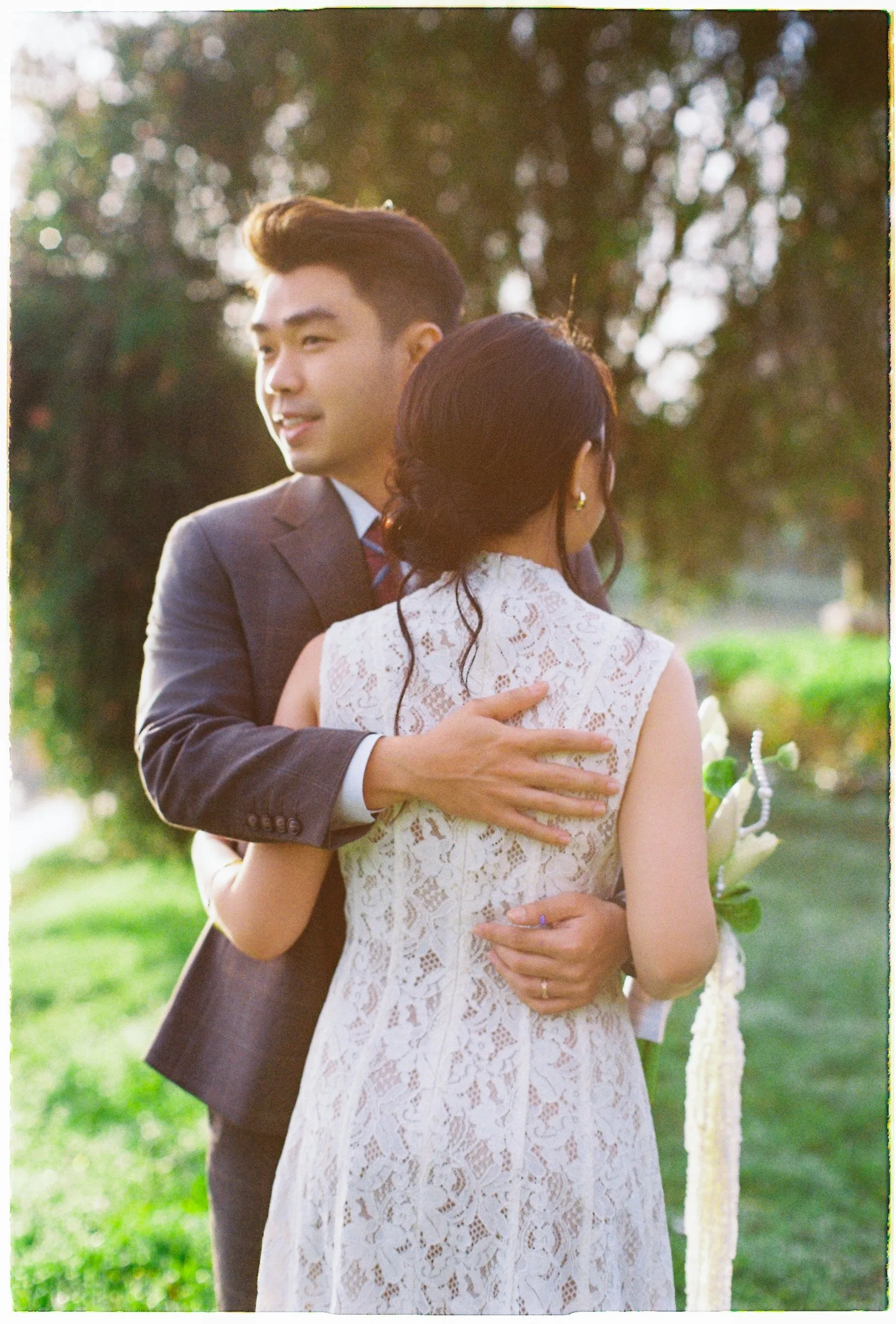 Couple embracing on the grass by the lake in Da Lat
