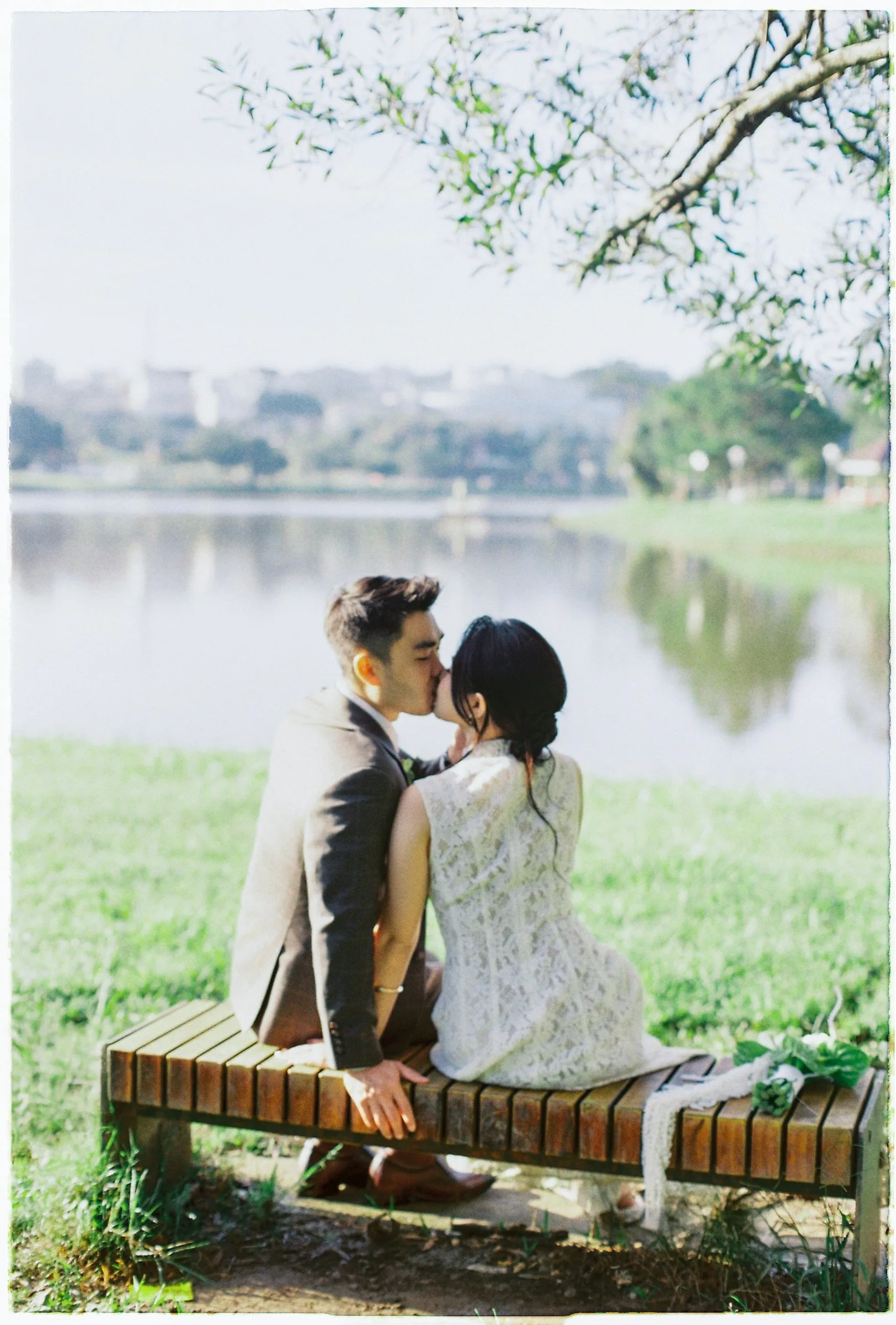 Couple kissing on a wooden bench by Xuan Huong Lake, Da Lat
