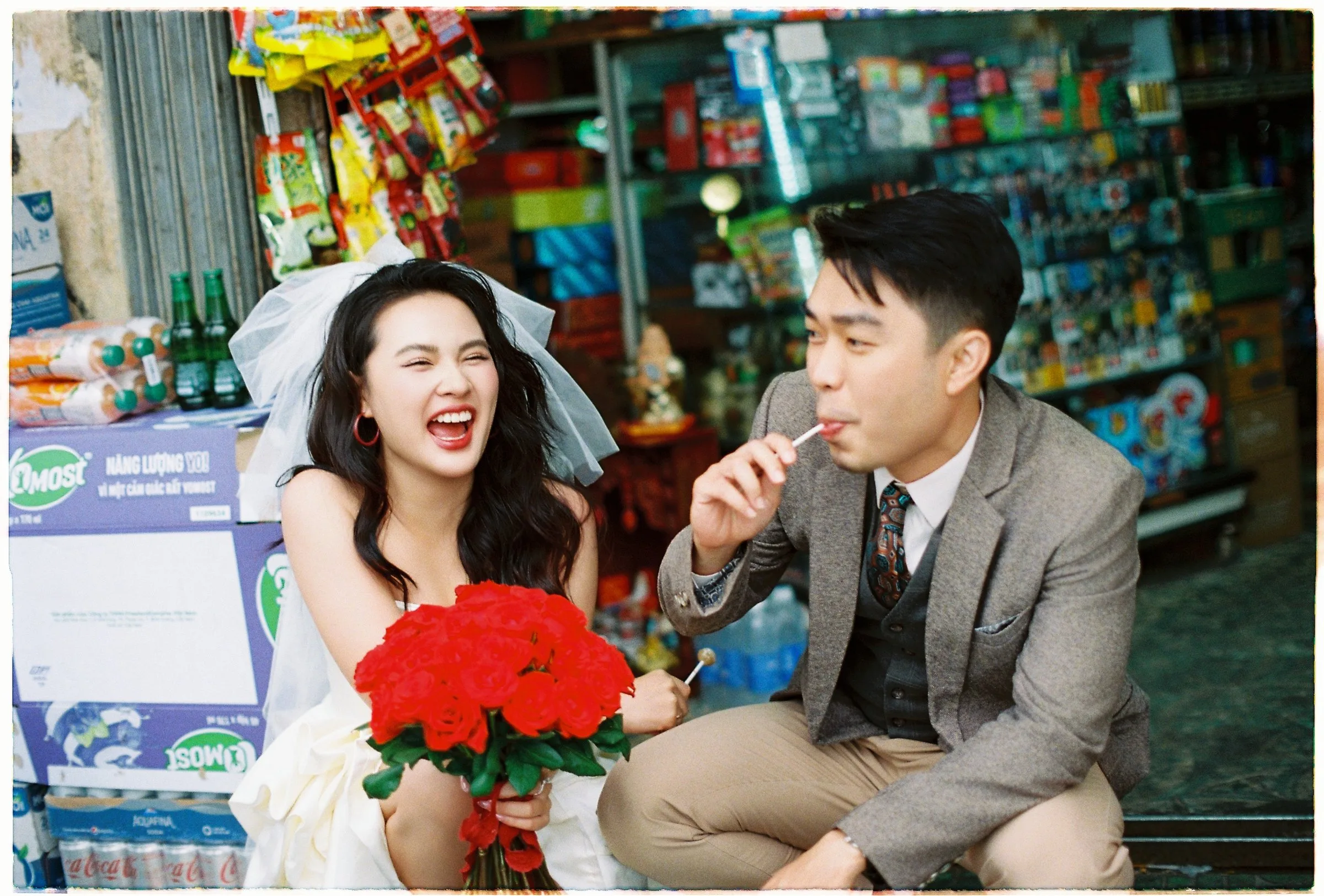 Bride laughing with red roses at a little shop in Da Lat