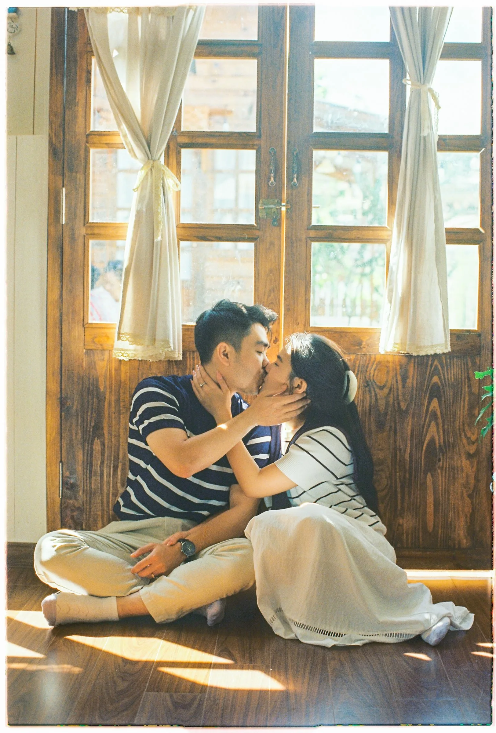 A couple sharing a quiet moment by a wooden window at their Da Lat pre-wedding on film by TIMO Wedding