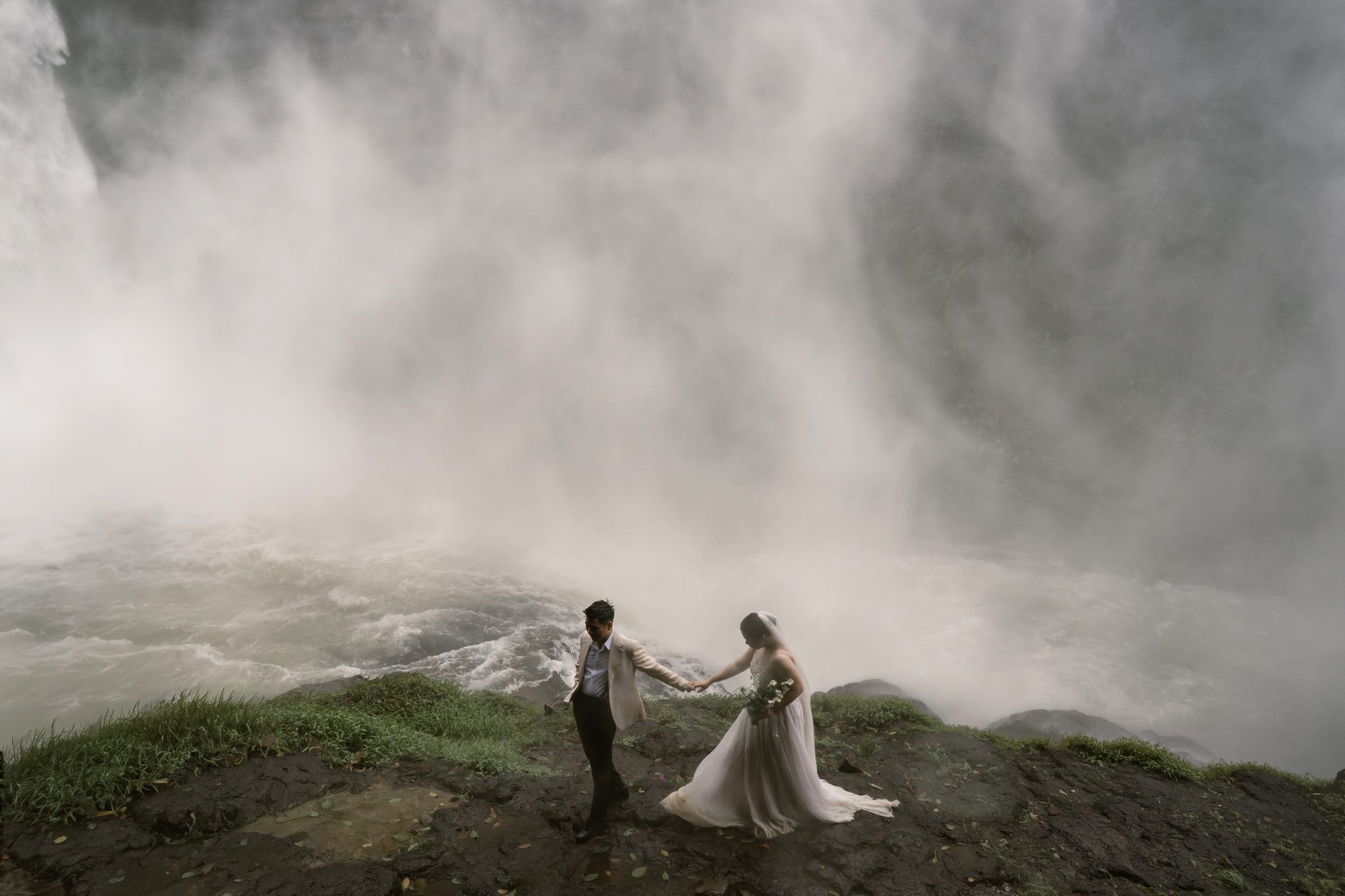 Two figures dwarfed by Dambri, one of the tallest waterfalls in Vietnam's Central Highlands.