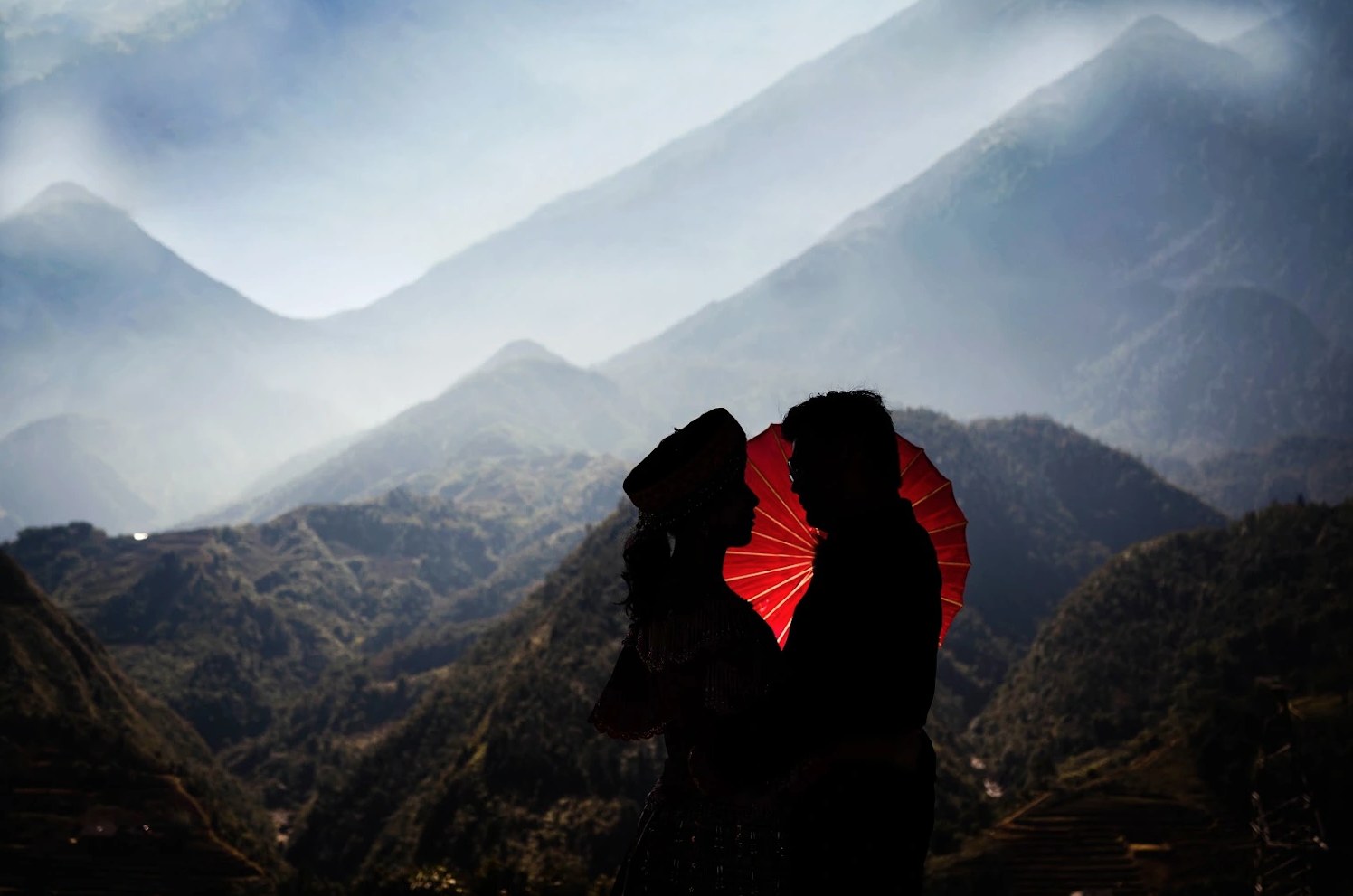 A red umbrella against the misty peaks and terraced fields of Sapa.