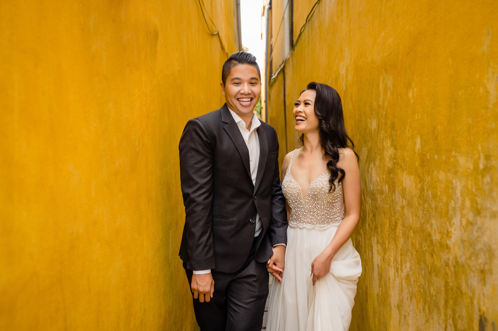 Holding hands and laughing down a narrow yellow lane in Hoi An's old town.