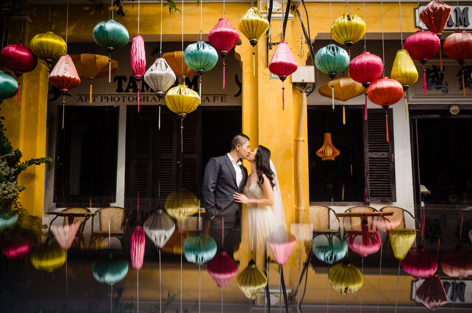 Mid-kiss beneath a curtain of silk lanterns in every colour.