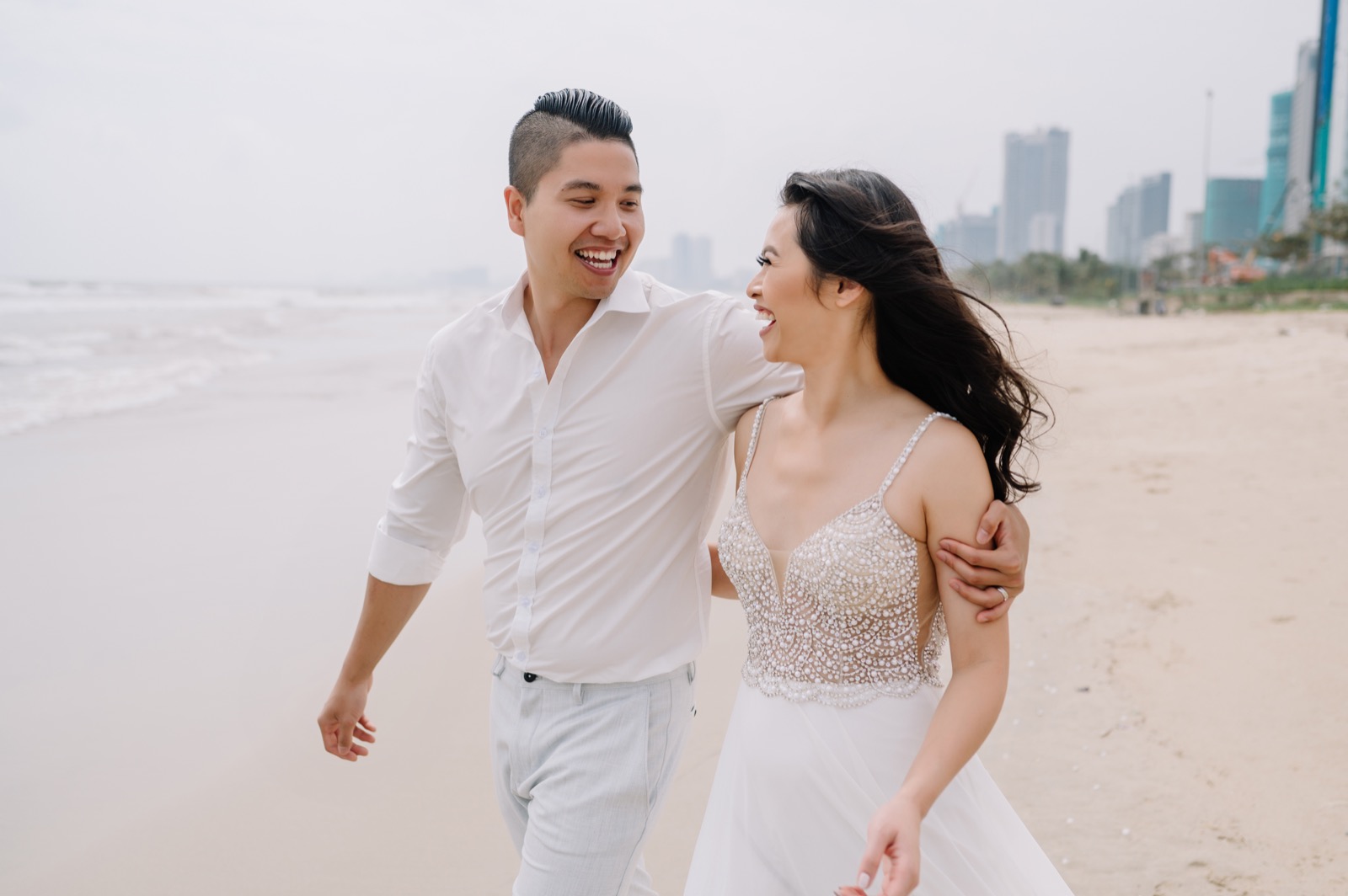 Laughing on the beach with the Da Nang skyline behind.