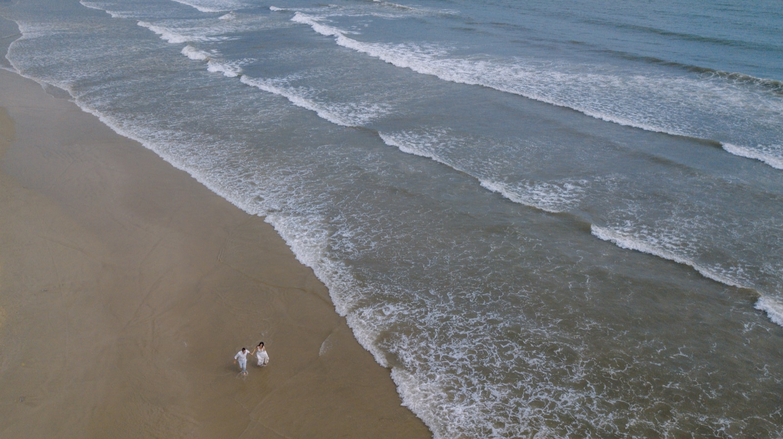 A drone's view of the shoreline, and the two of them walking it together.