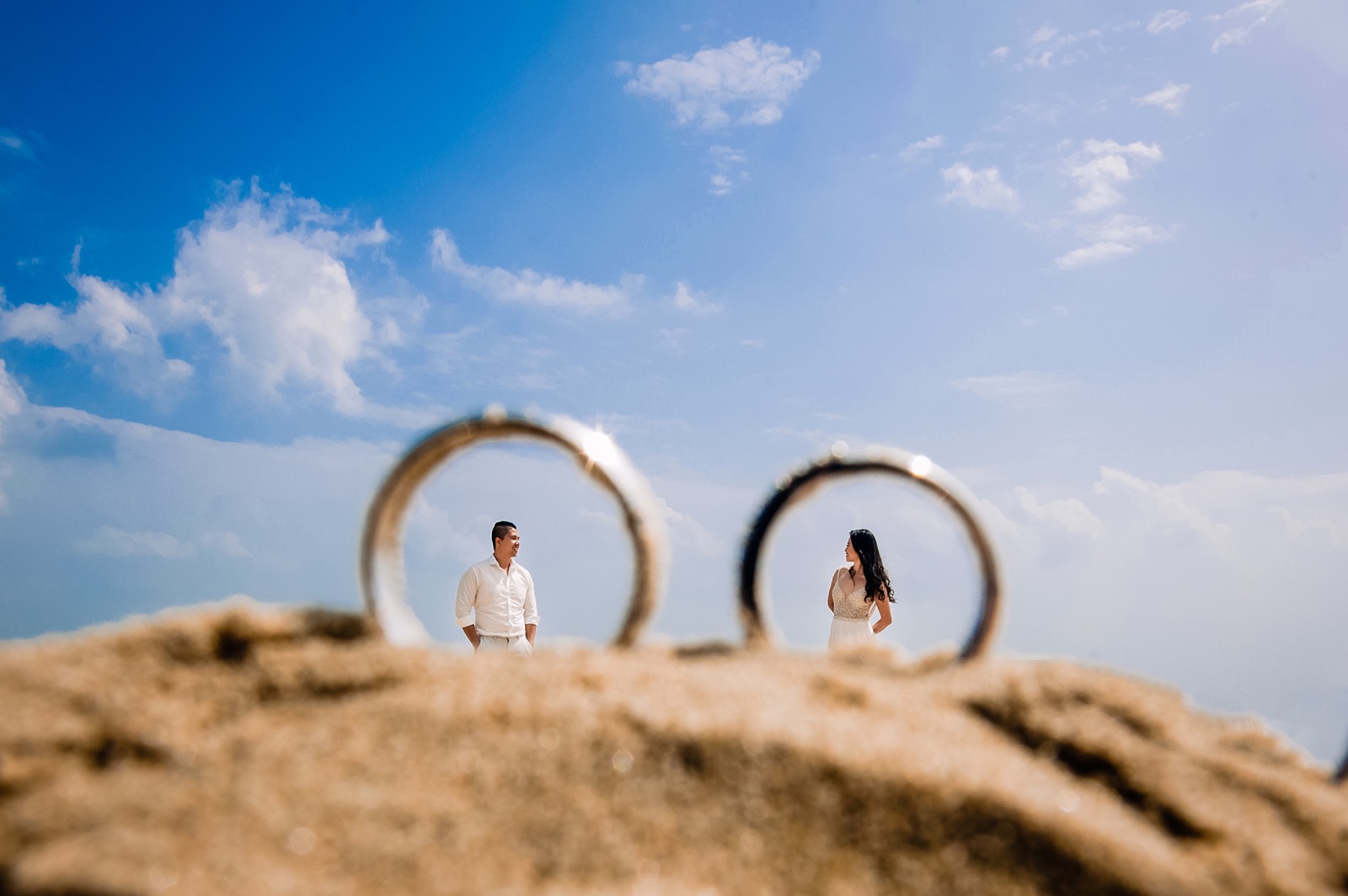 Framed through their own two rings, resting on the sand.