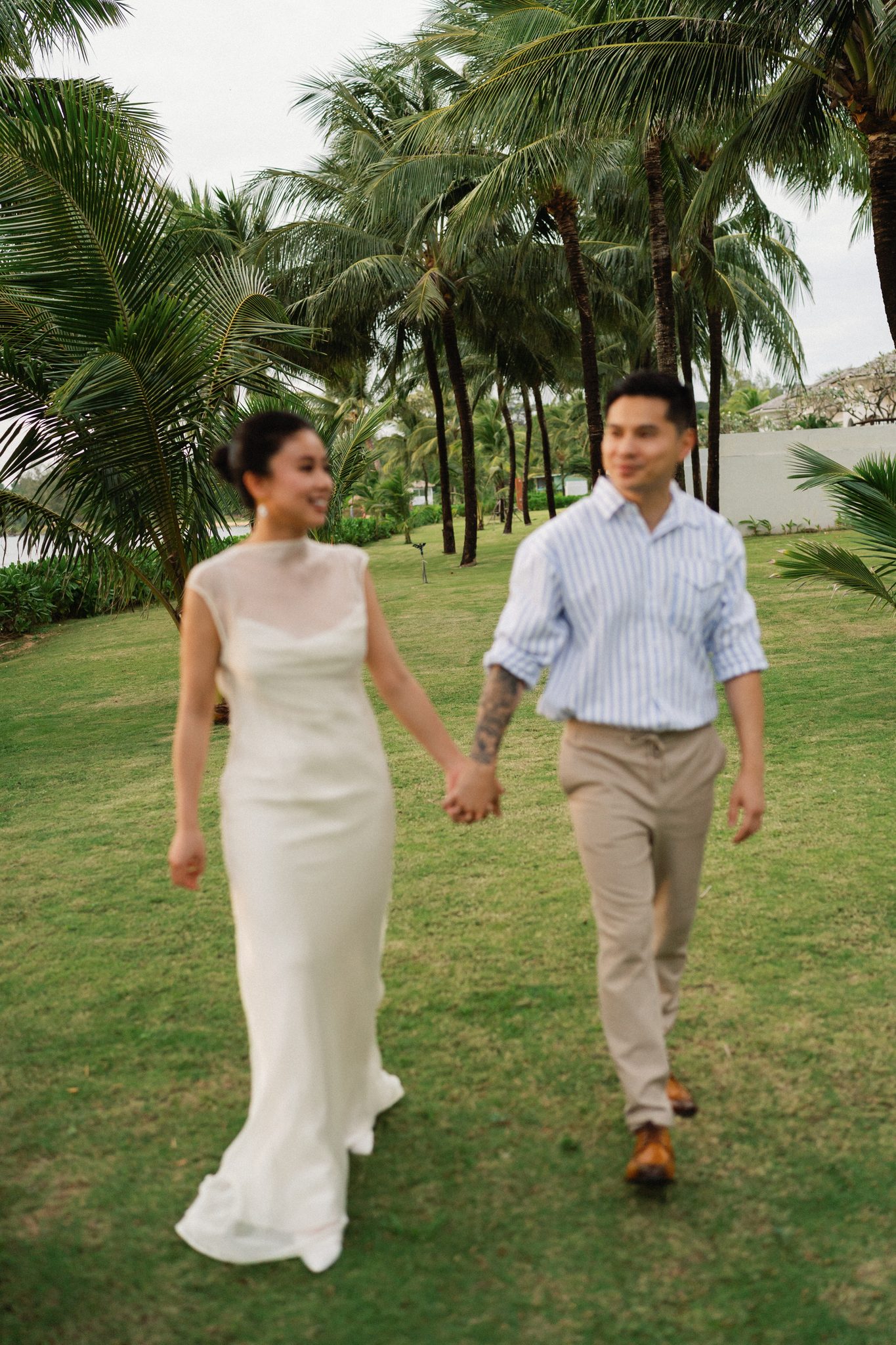 Hand in hand under towering palms in a Phu Quoc resort garden.