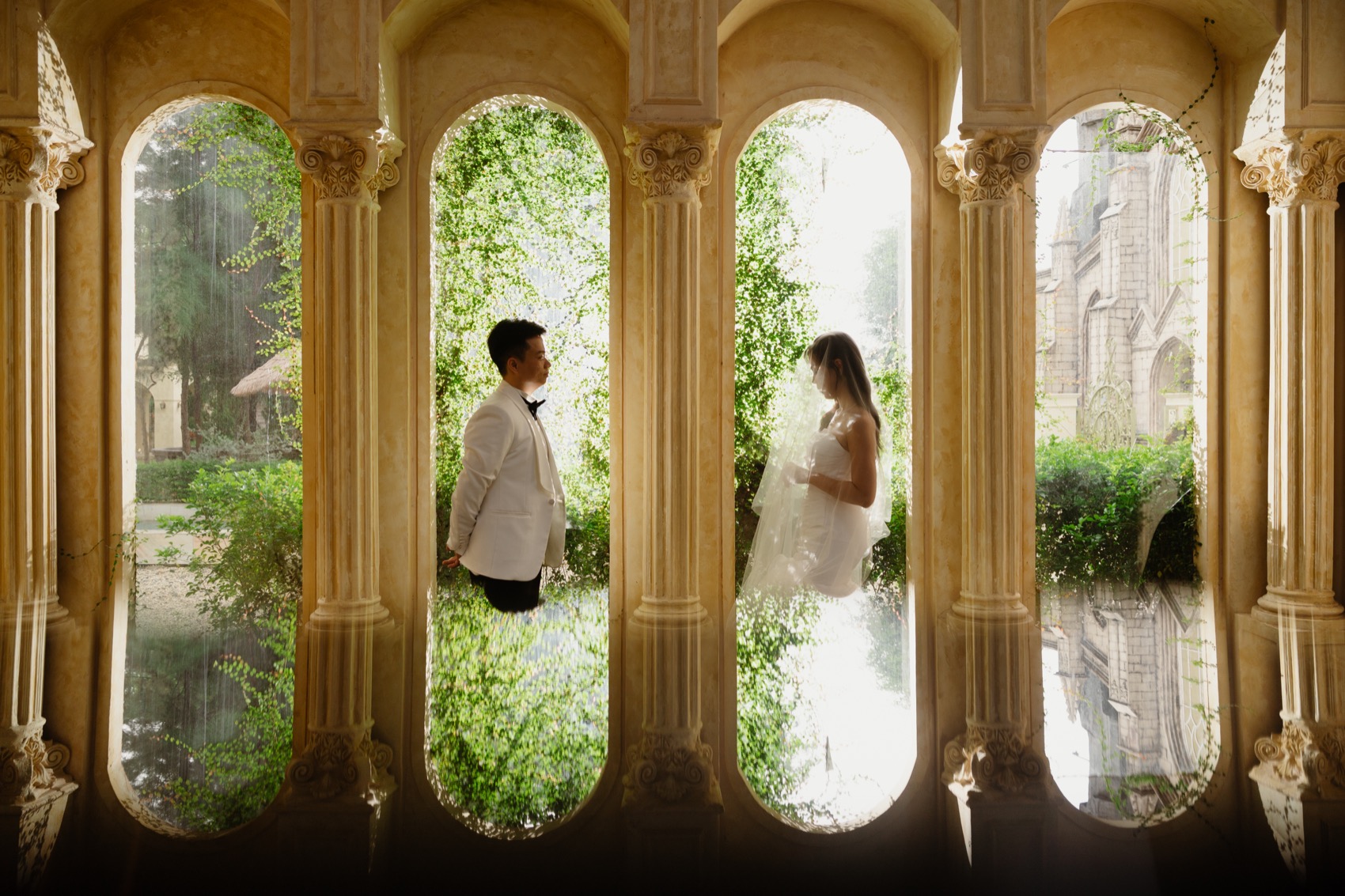 Couple framed by tall arched colonial windows in Saigon