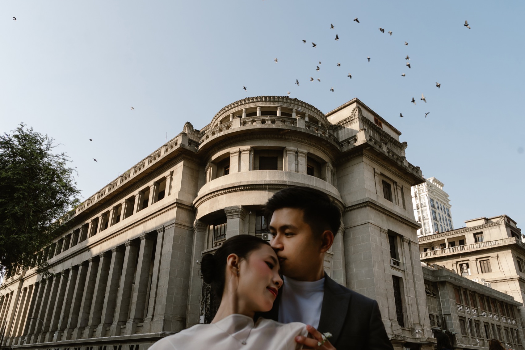 Couple kissing in front of a grand colonial building in central Saigon