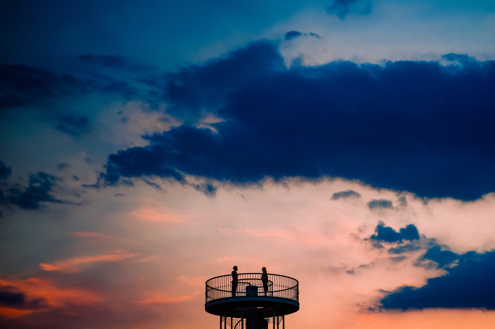 A couple on a viewing tower against a dramatic Saigon sunset