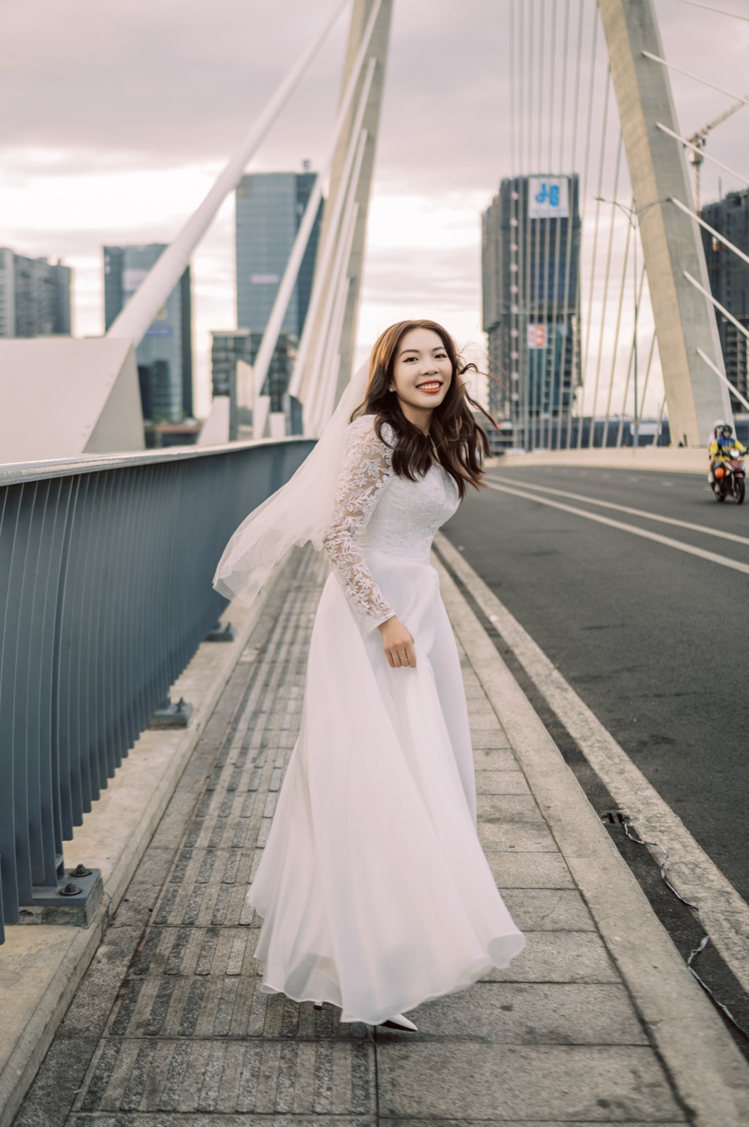 The bride on the cable-stayed bridge over the Saigon River, the city rising in the distance.