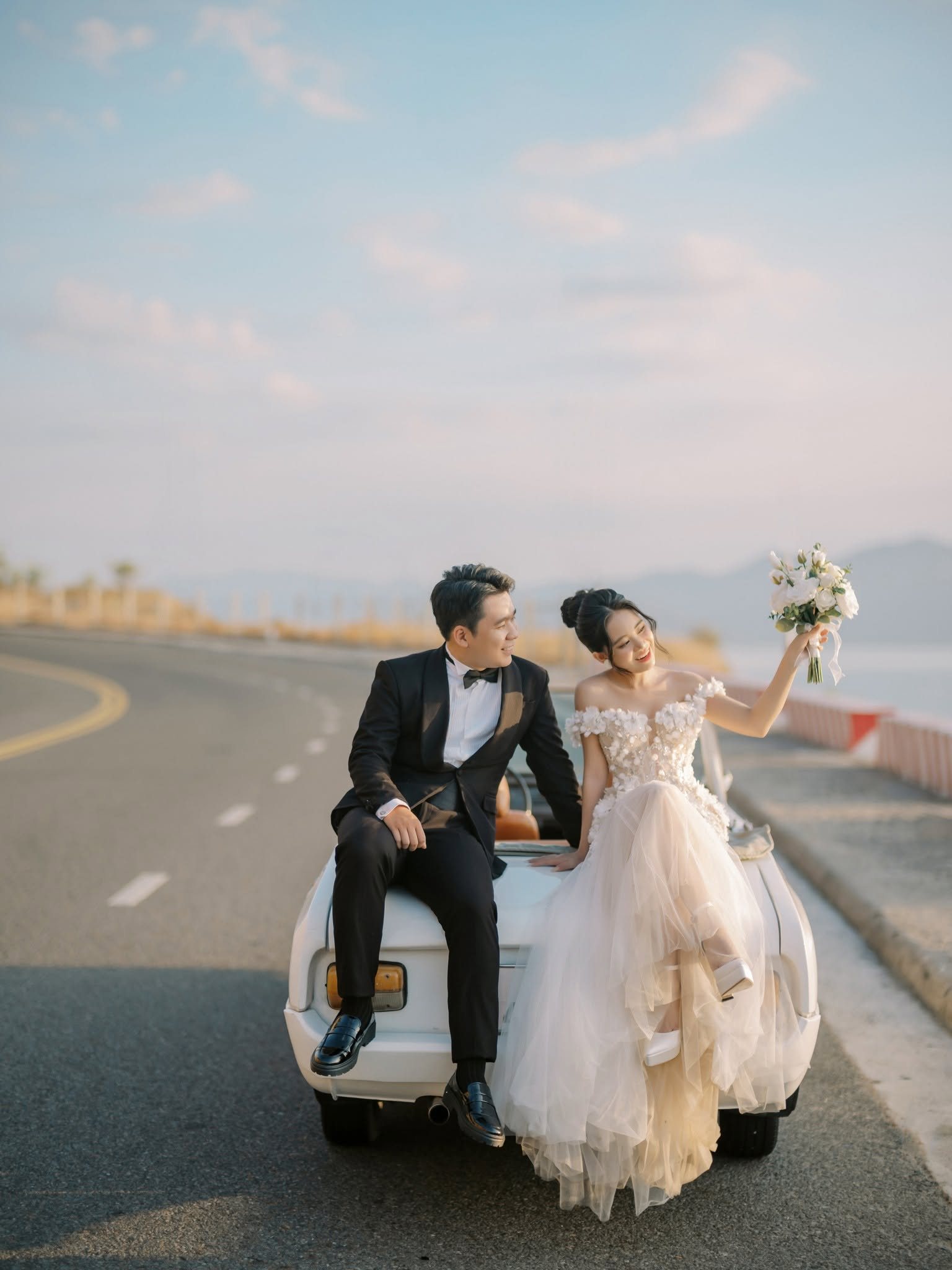 Chung perched on the bonnet, bouquet in hand, Trung close by.