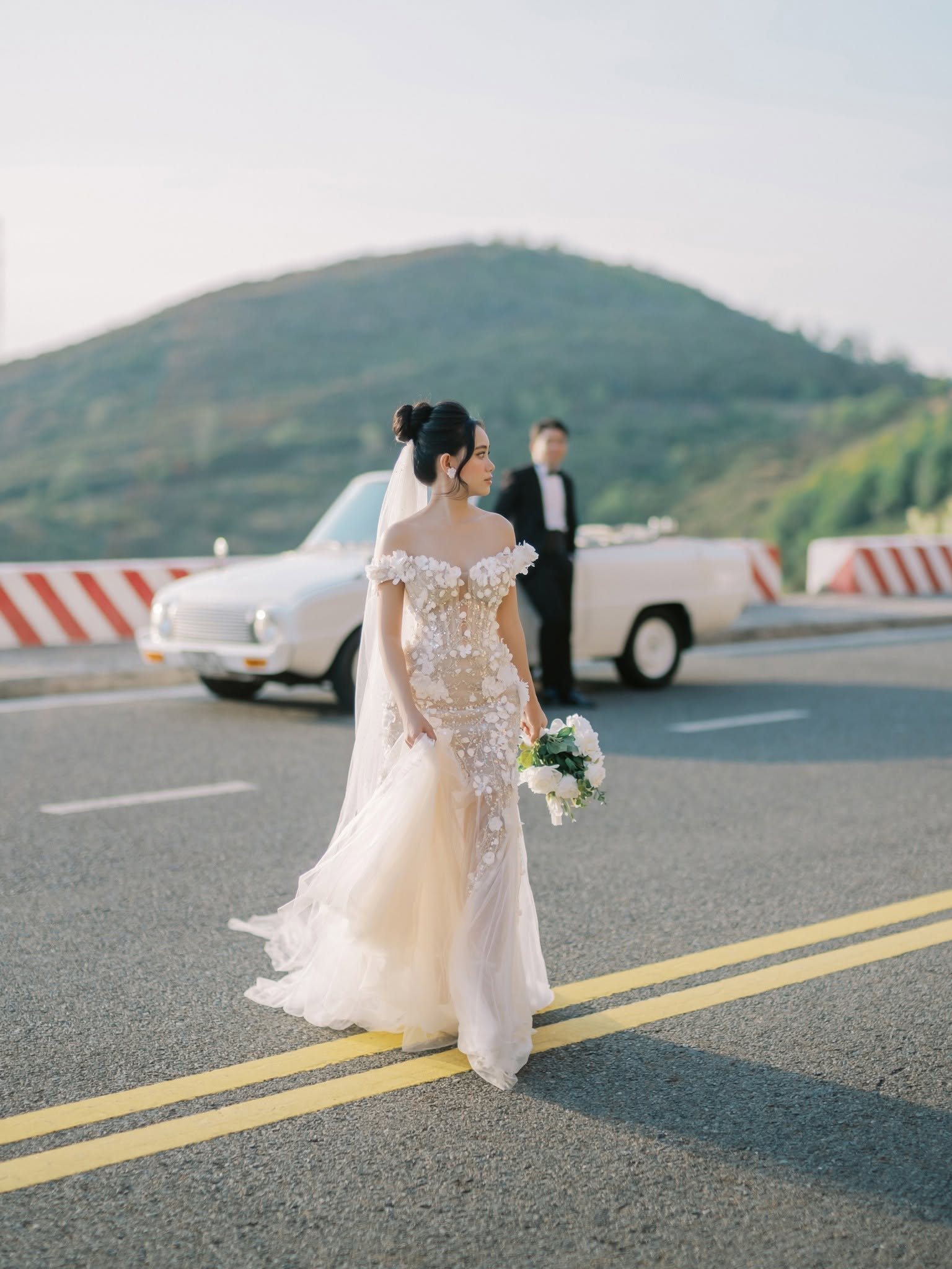 Chung walking the road, mountains folding into the distance.
