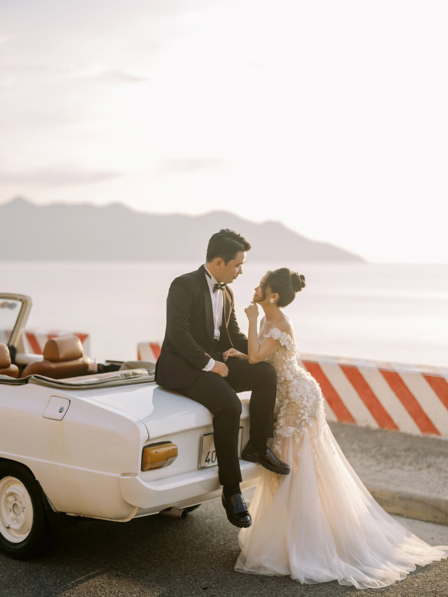 Sitting together on the back of the convertible, facing the water.