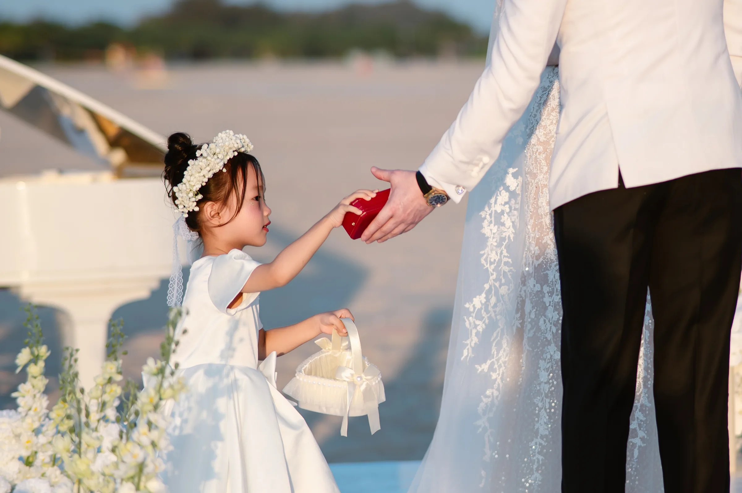A flower girl handing the ring box to the groom at a Ho Tram beach wedding