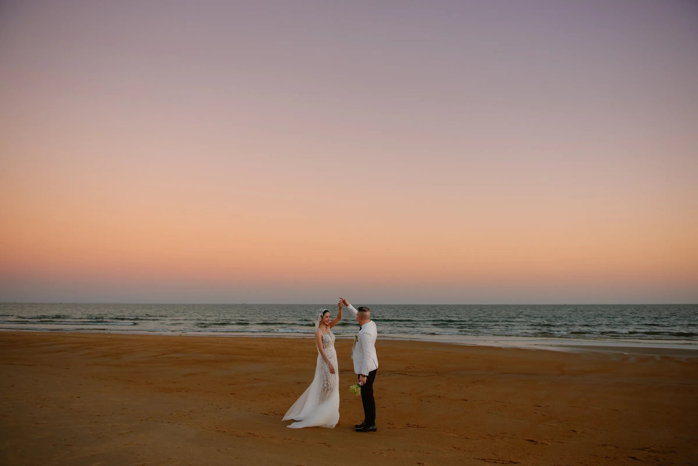 A couple dancing on the sand at golden hour during a beach wedding at Melia Ho Tram, in Vietnam's dry season.