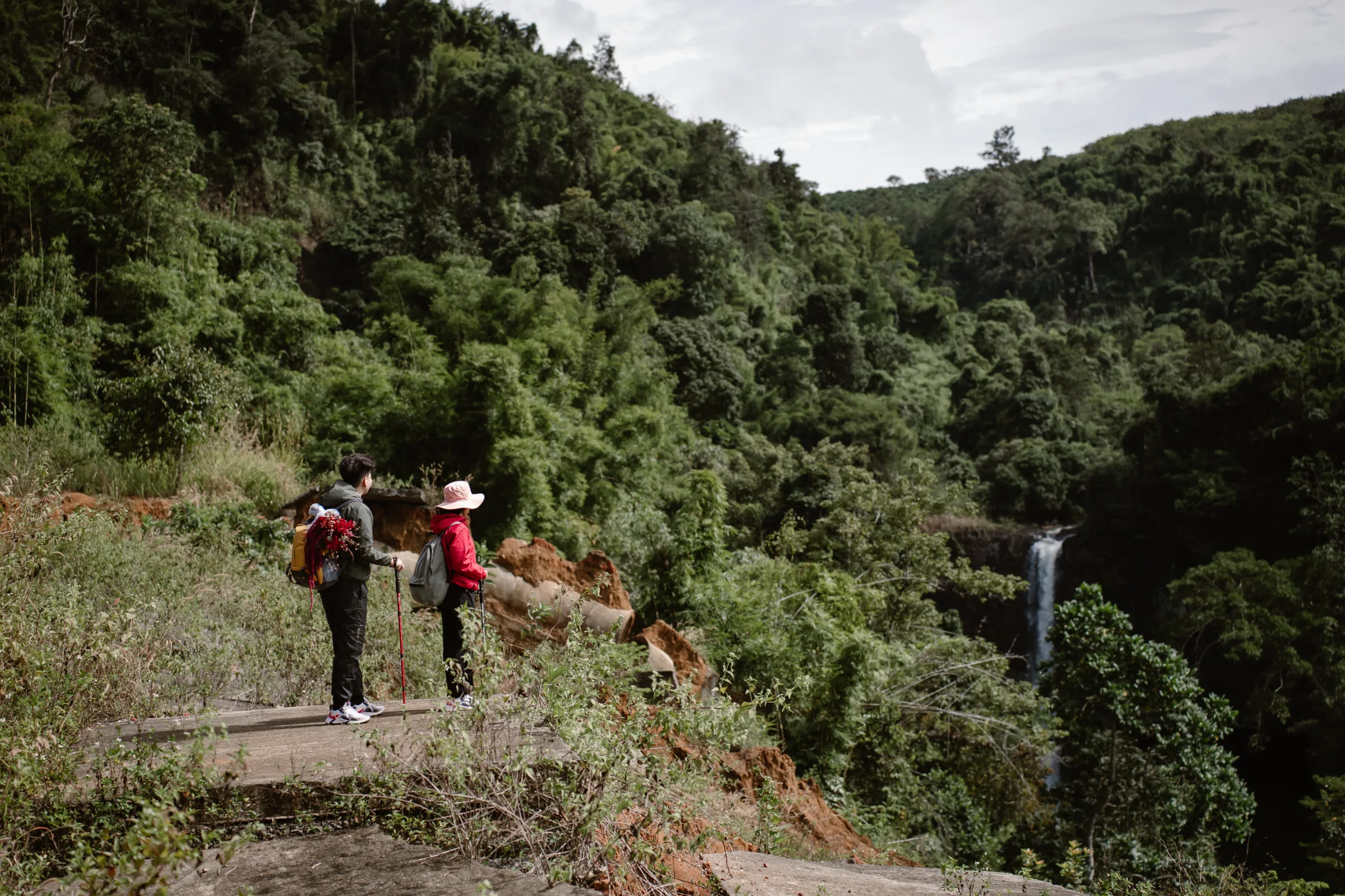 Couple trekking a jungle trail toward a waterfall on their Vietnam elopement
