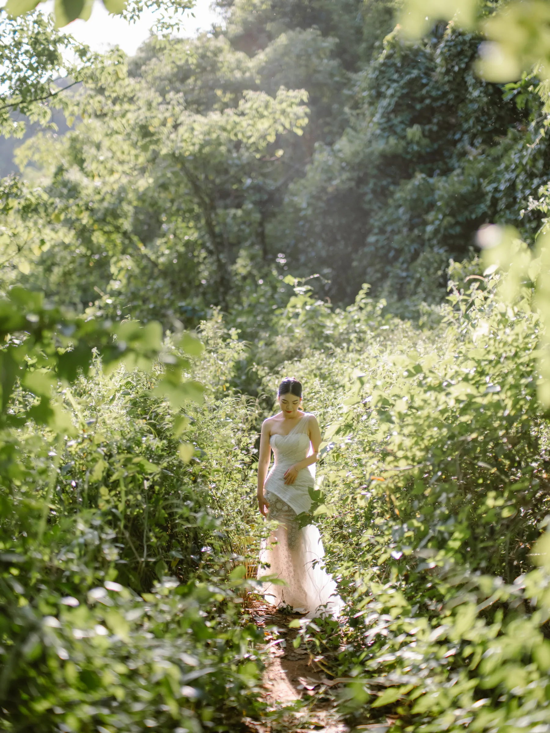 Dịu in her gown, on the forest trail down to the falls.