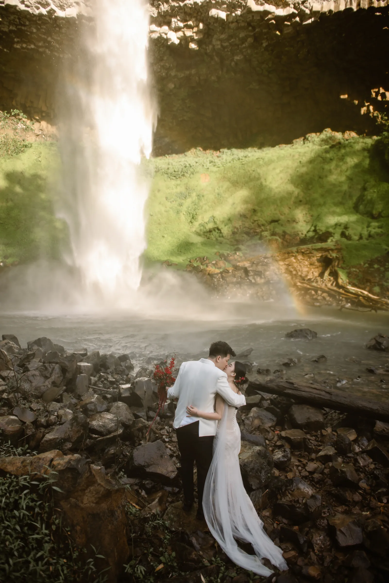 Couple embracing at the base of a waterfall during an adventure elopement in Vietnam