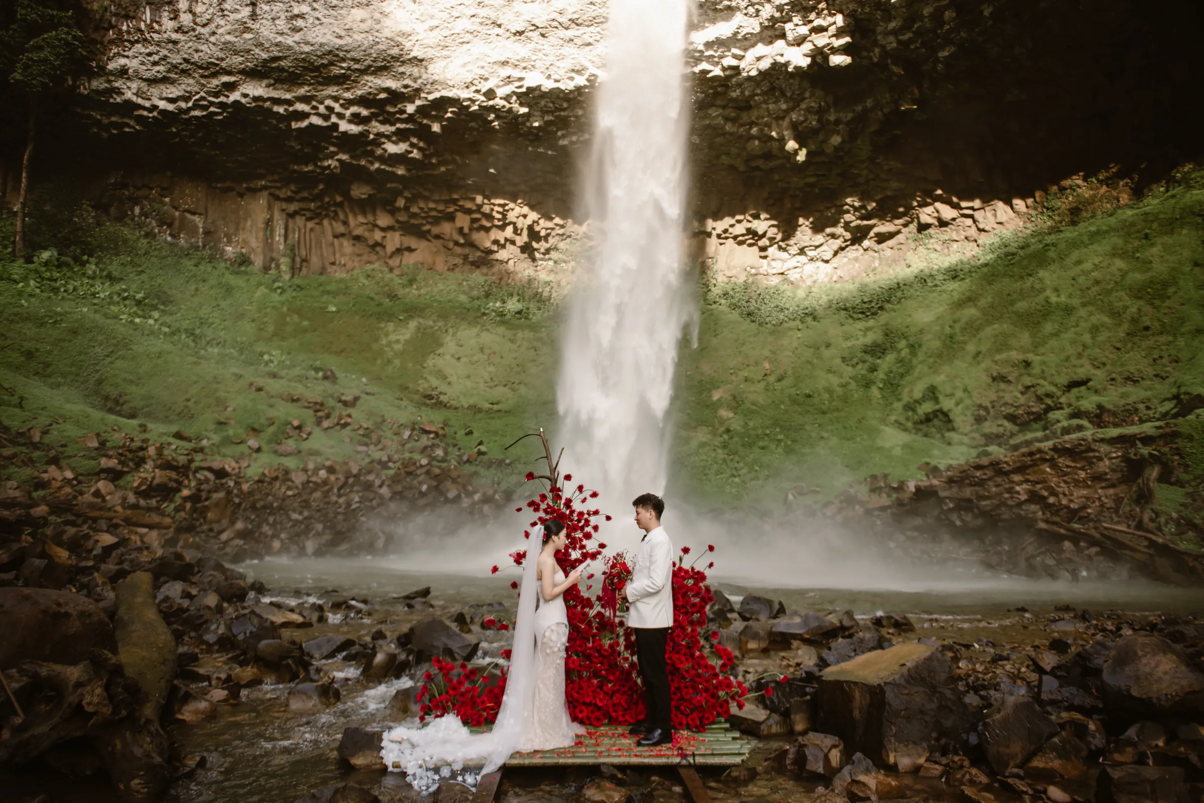 Couple tiny at the base of a huge waterfall, adventure elopement in the Central Highlands