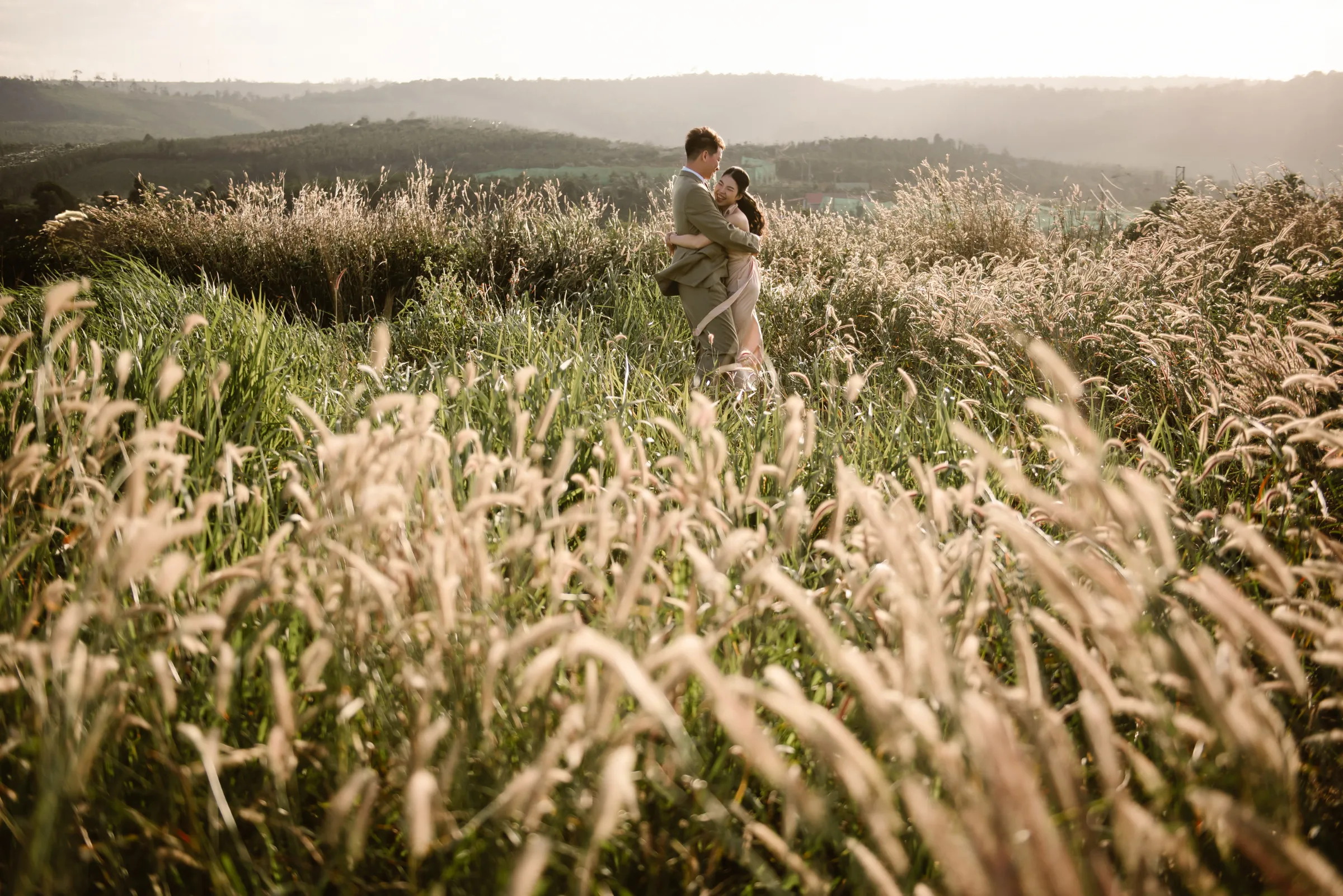 Couple in tall golden grass at sunset during an intimate elopement in Vietnam