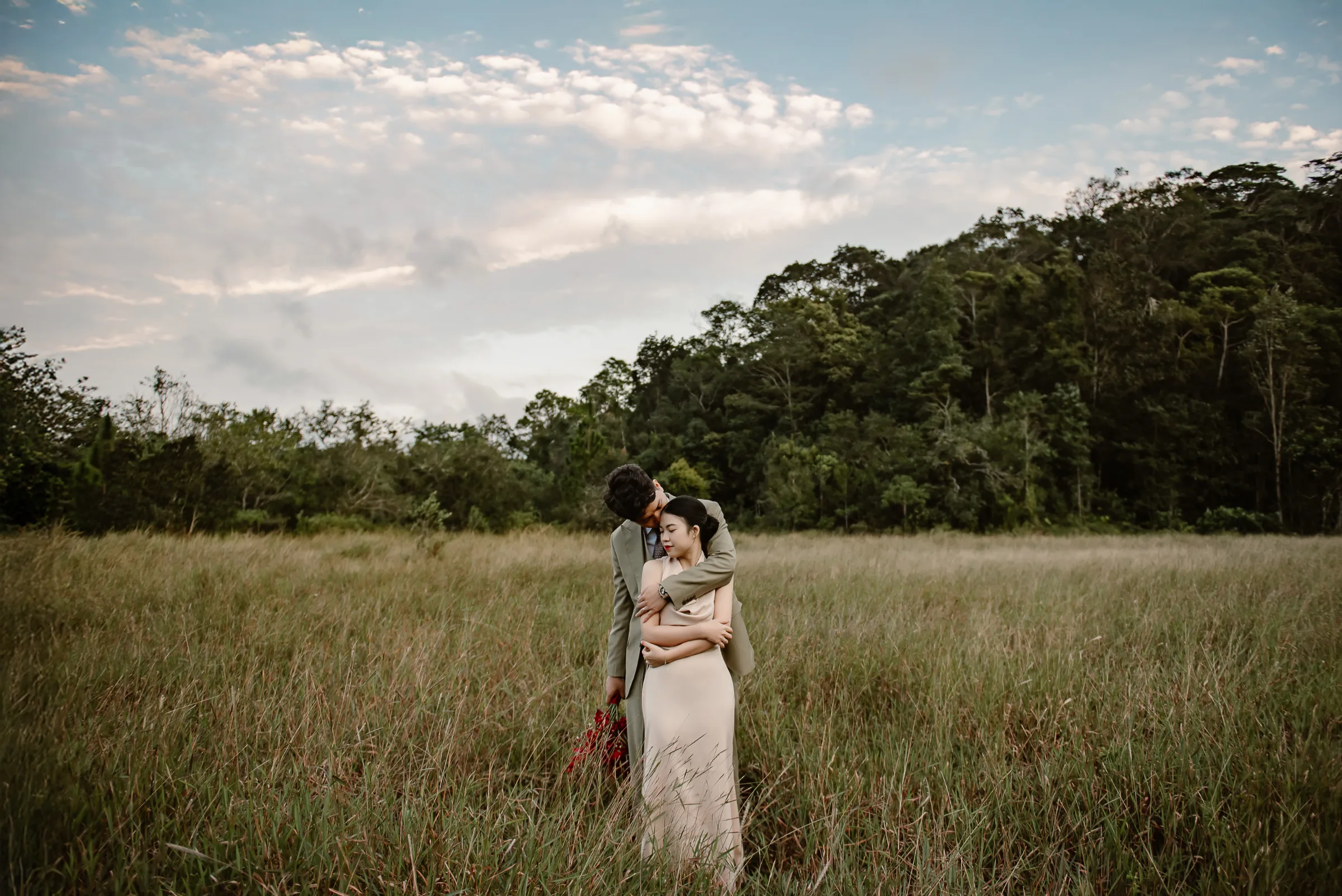Couple embracing in a grassy meadow at golden hour, Vietnam elopement