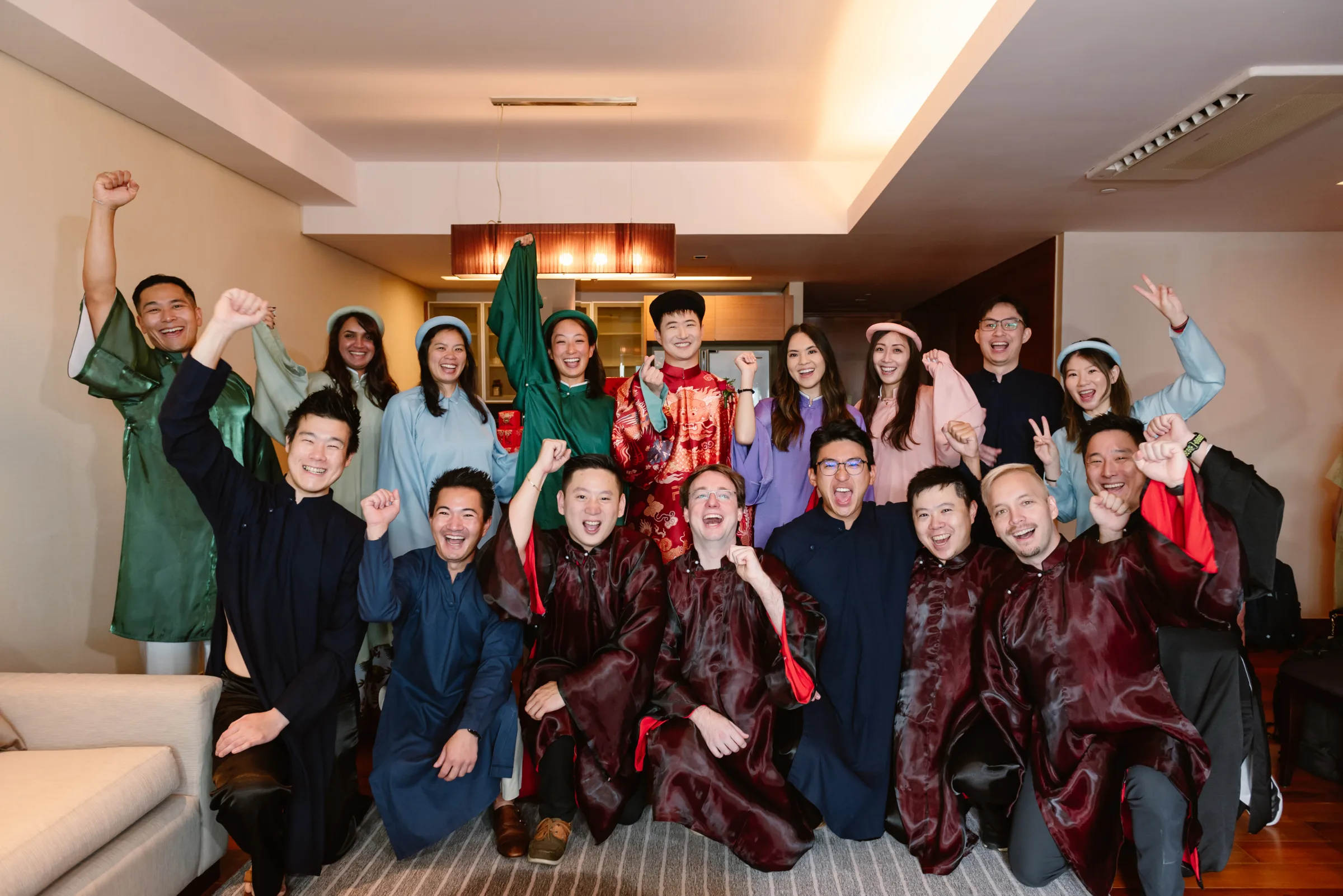 Family and friends in colourful ao dai celebrating together at a cross-cultural Vietnamese wedding.