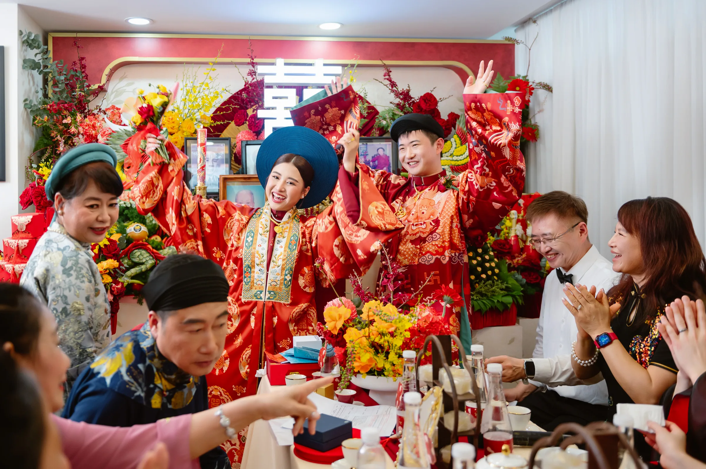 A couple in red ao dai and khan dong at the family altar during their le gia tien, the heart of a traditional Vietnamese wedding ceremony.