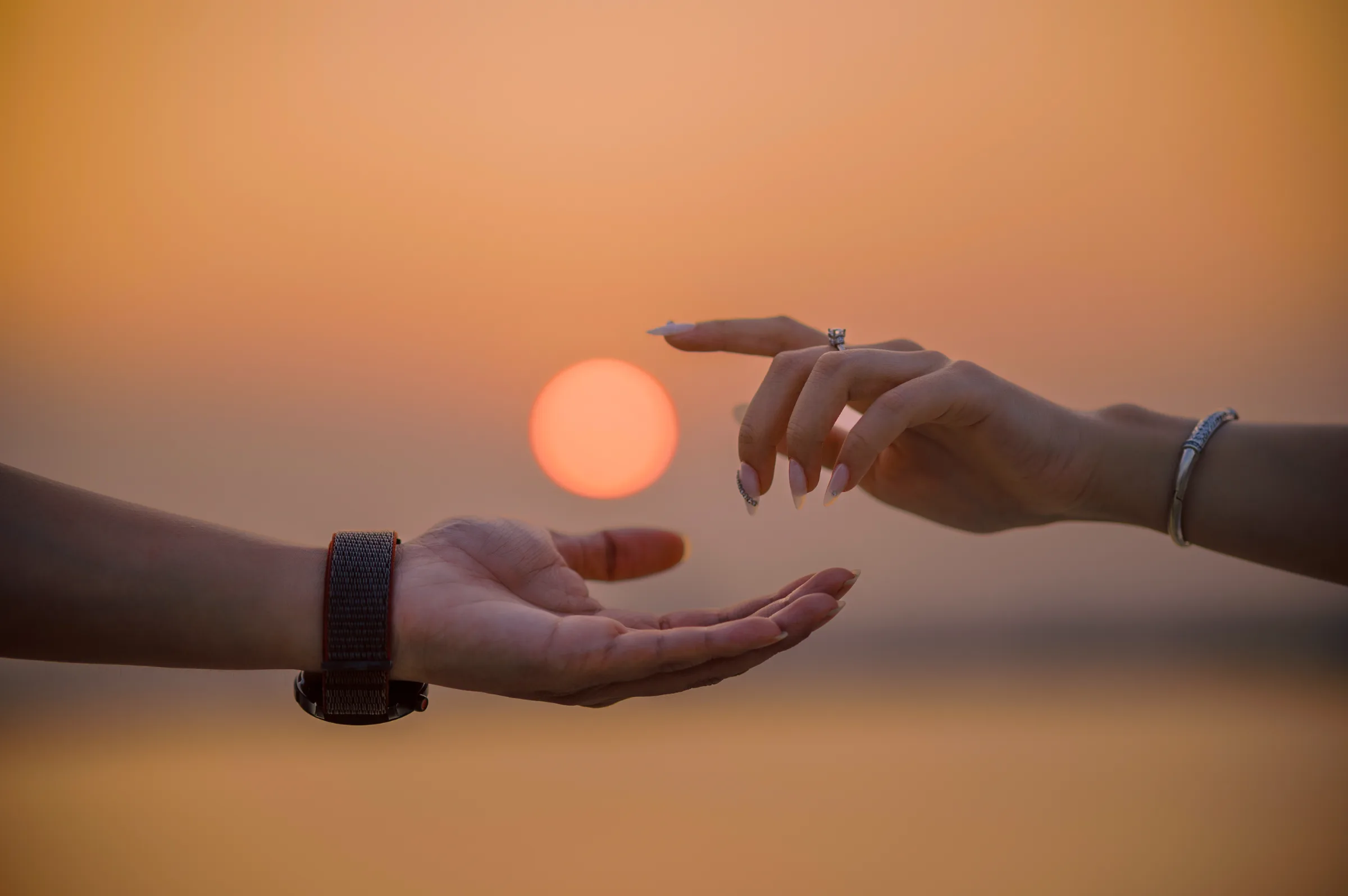 Two hands reaching toward each other around the setting sun, Phu Yen pre-wedding