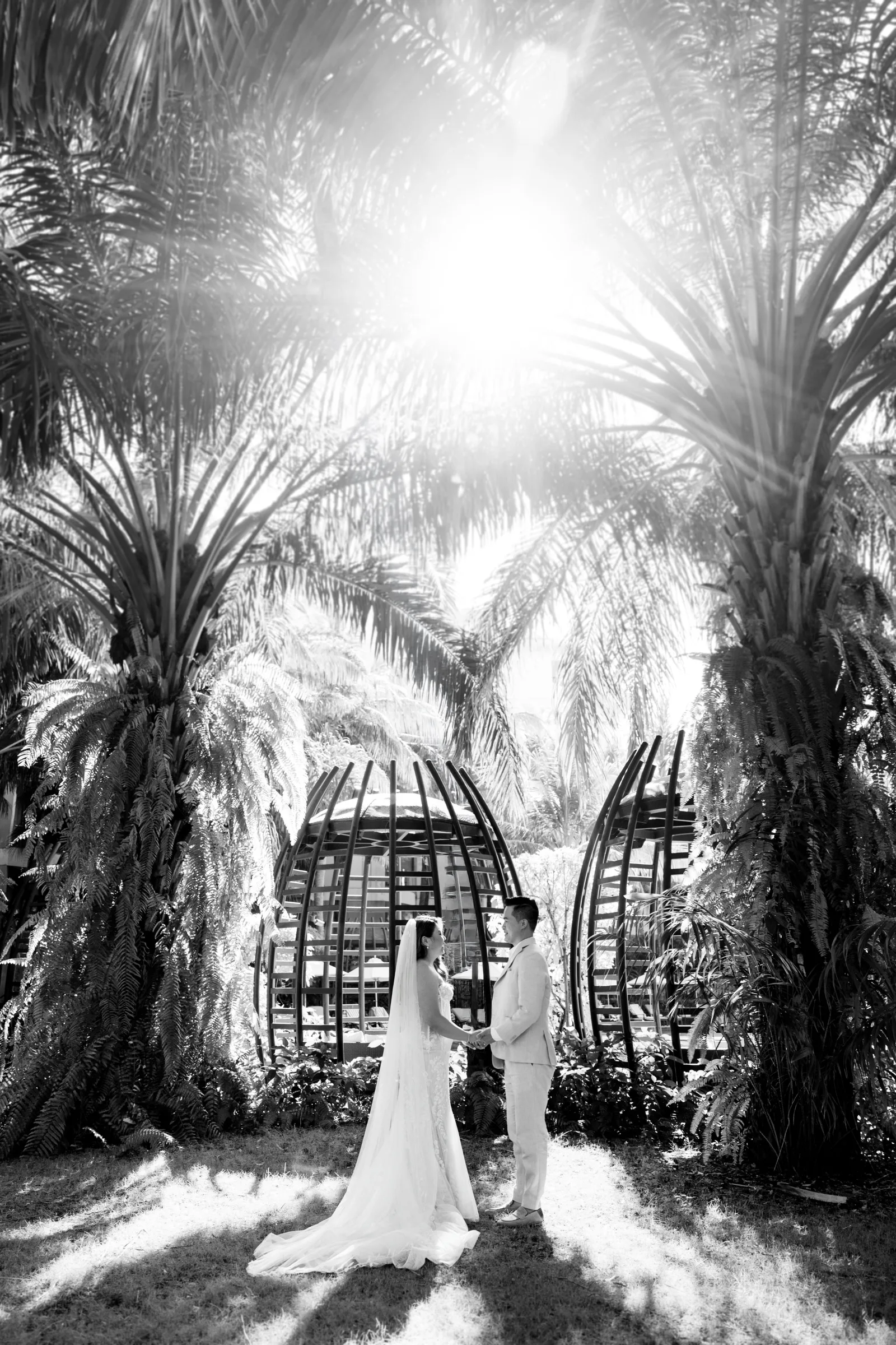 Black and white frame of the bride in a sunlit palm arch at Phu Quoc